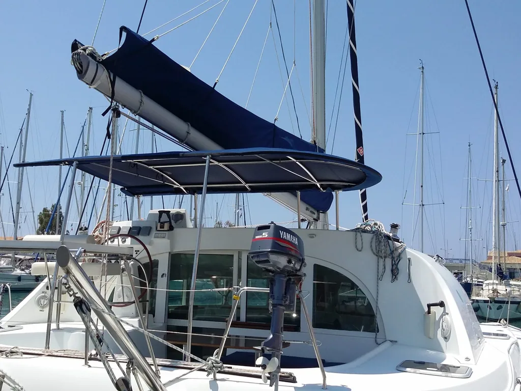 A navy bimini rigged over the cockpit of a catamaran in a marina