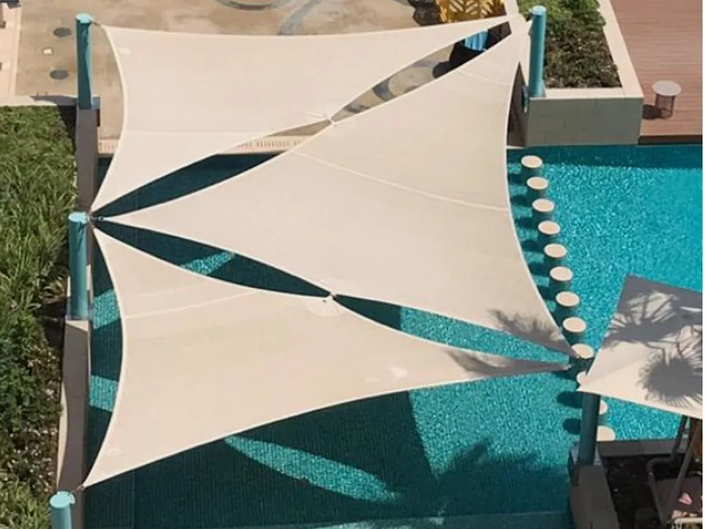 A white shade sail tensioned across the front of a stone villa