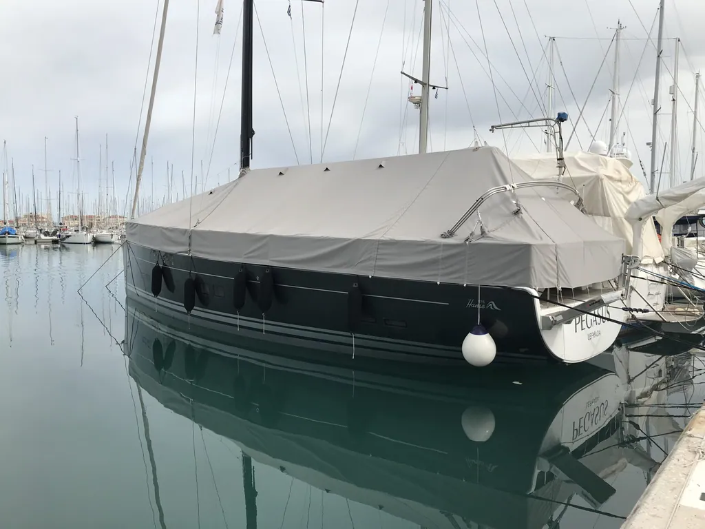 A covered yacht mirrored in still harbour water