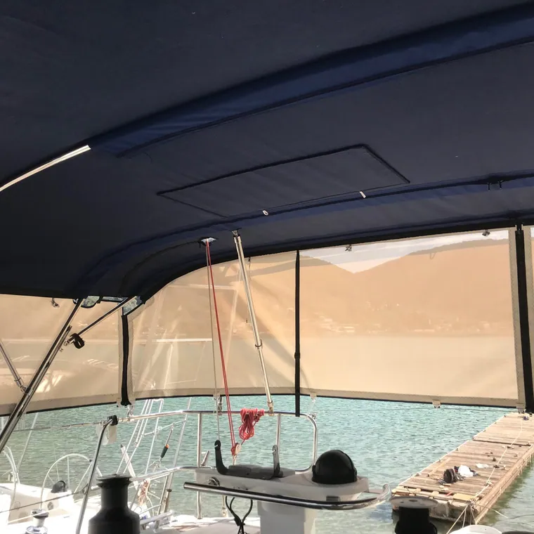 Navy bimini and clear side panels over the cockpit of a yacht alongside