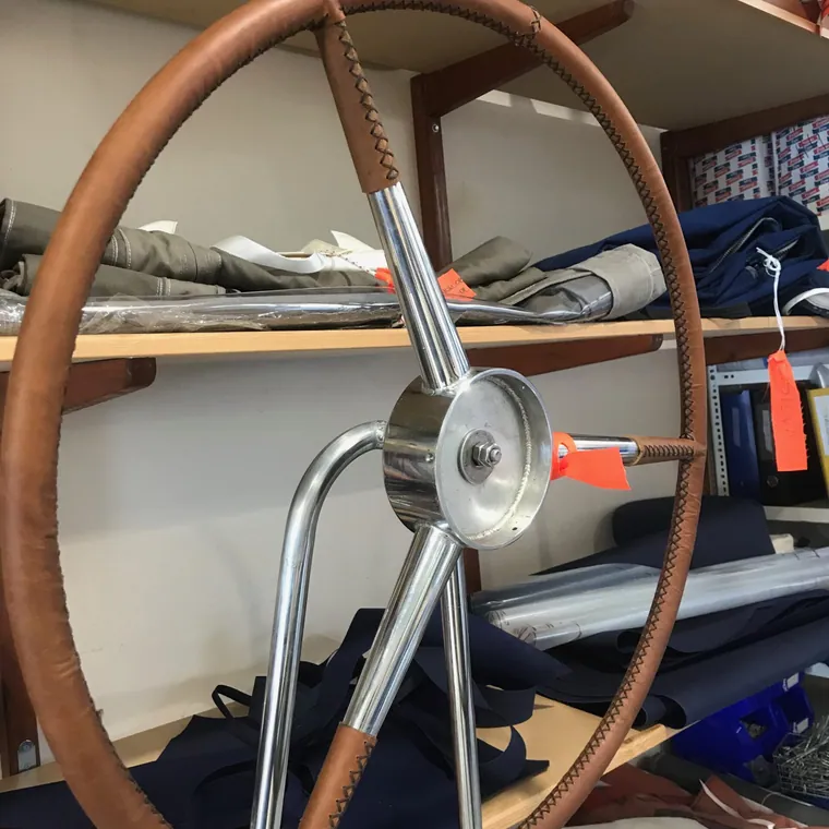Wooden yacht wheel rebuilt and wrapped in tan leather in the workshop