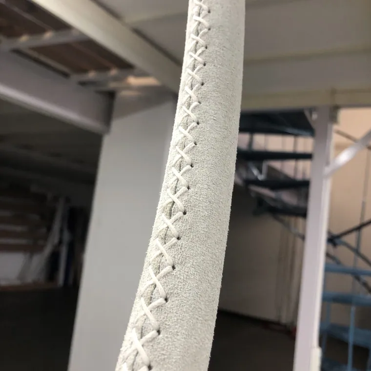 Close view of cross-stitching along a white leather wheel rim
