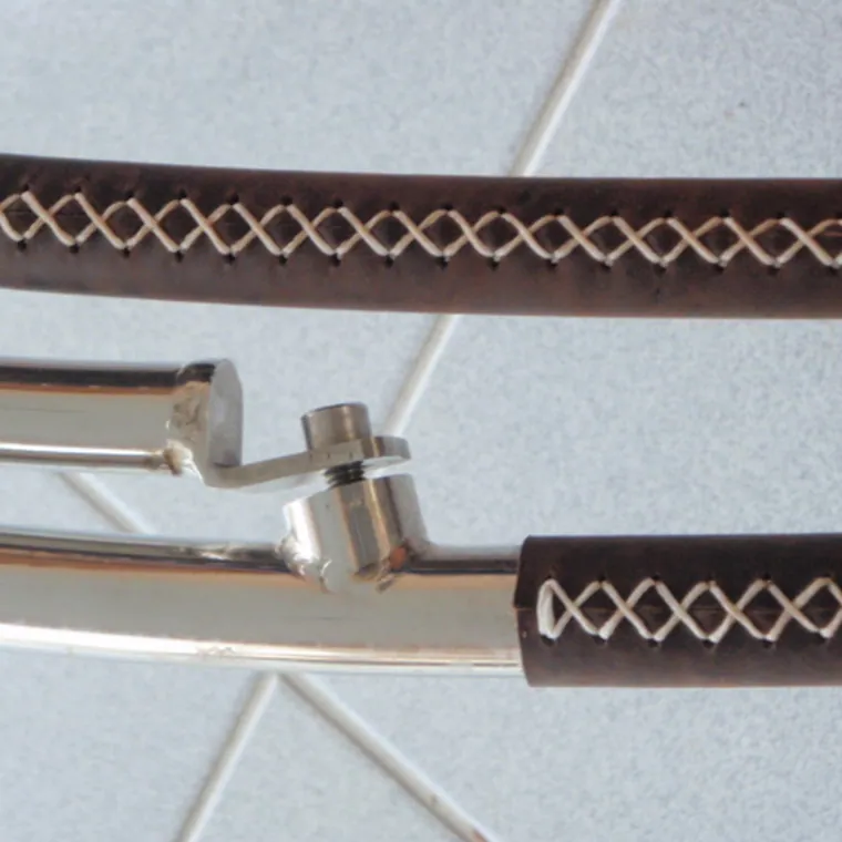 Two stainless rails wrapped in brown leather with contrast cross-stitching