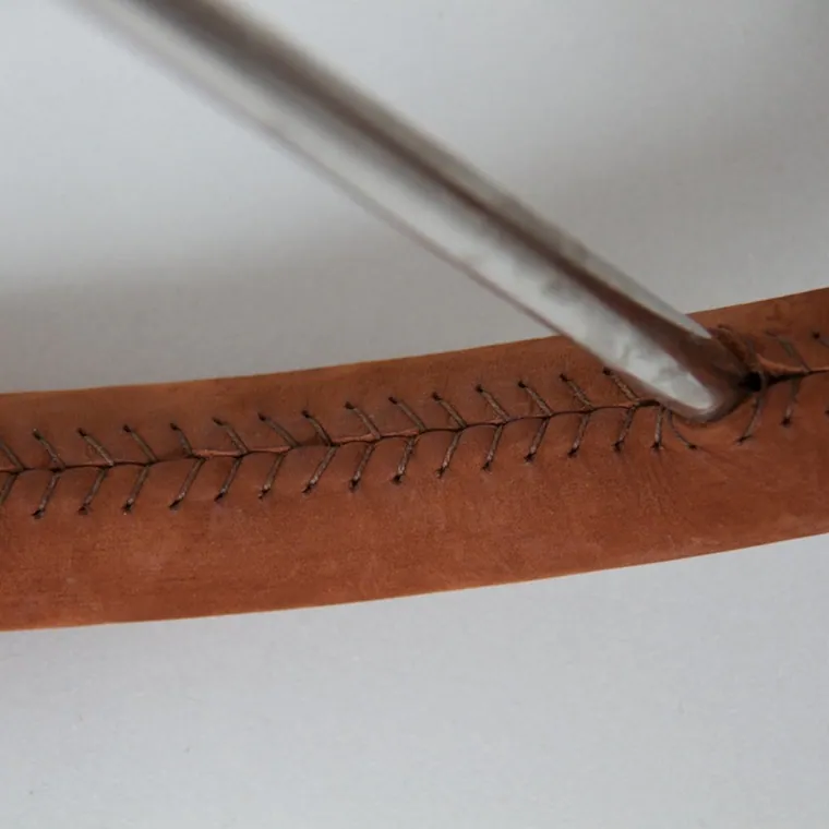 Detail of the seam on a tan leather wrap, stitch by stitch