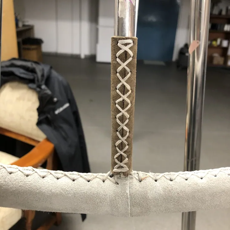 White leather wheel with cross-stitched rim on a workshop bench