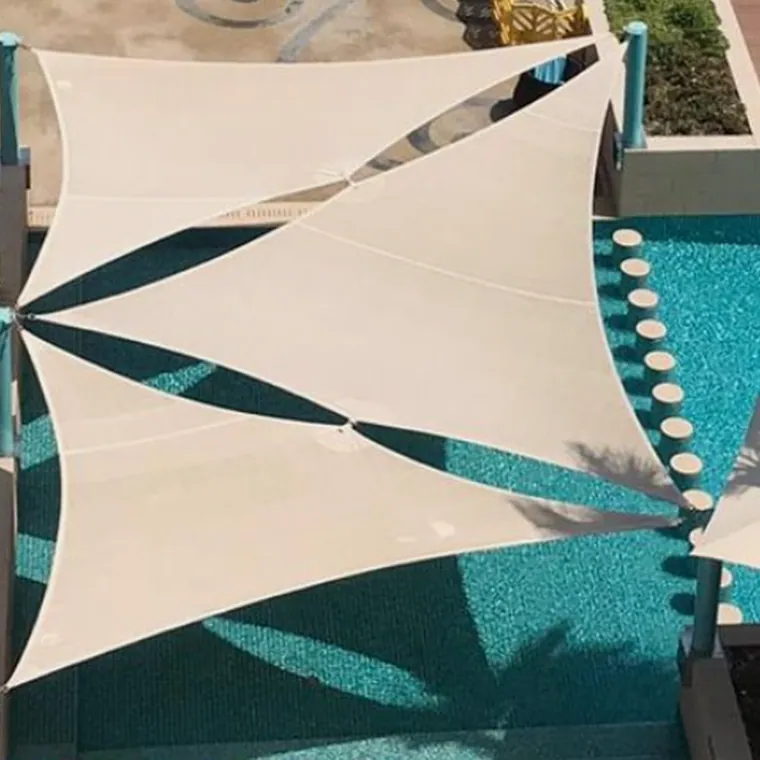 White shade sails tensioned over a turquoise pool and its deck