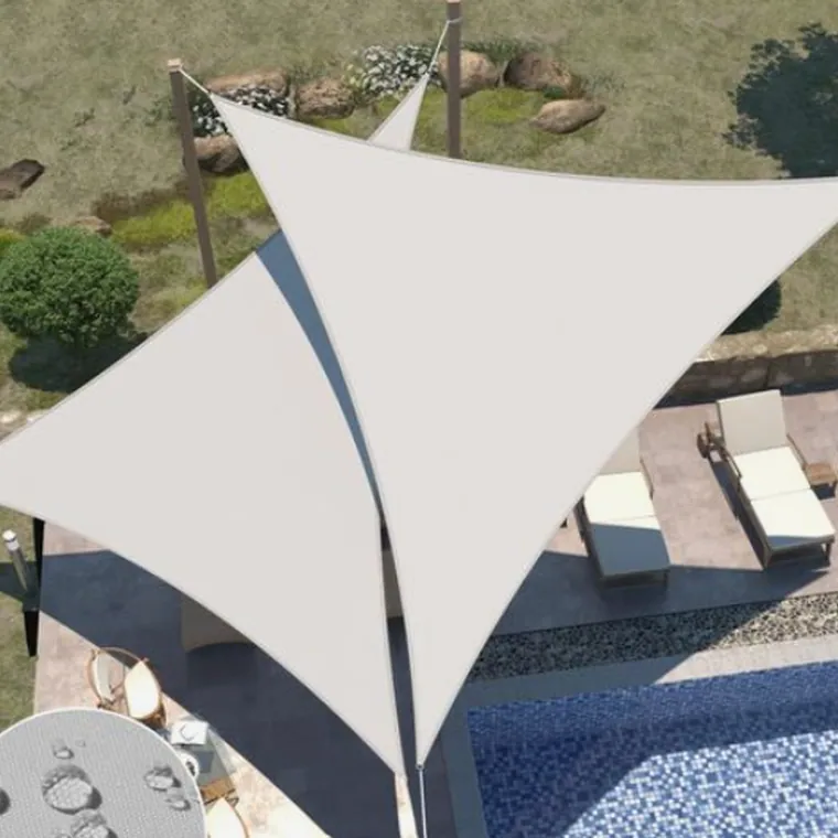 White shade sail on a mast over a paved garden terrace