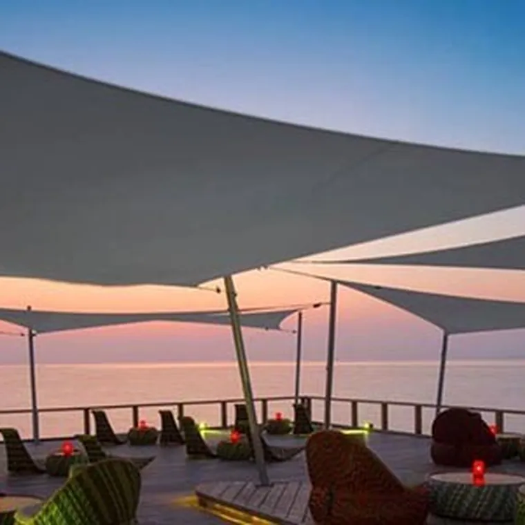 Shade sails over a seafront deck at sunset