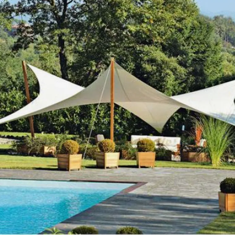 Pair of white shade sails on masts beside a garden pool