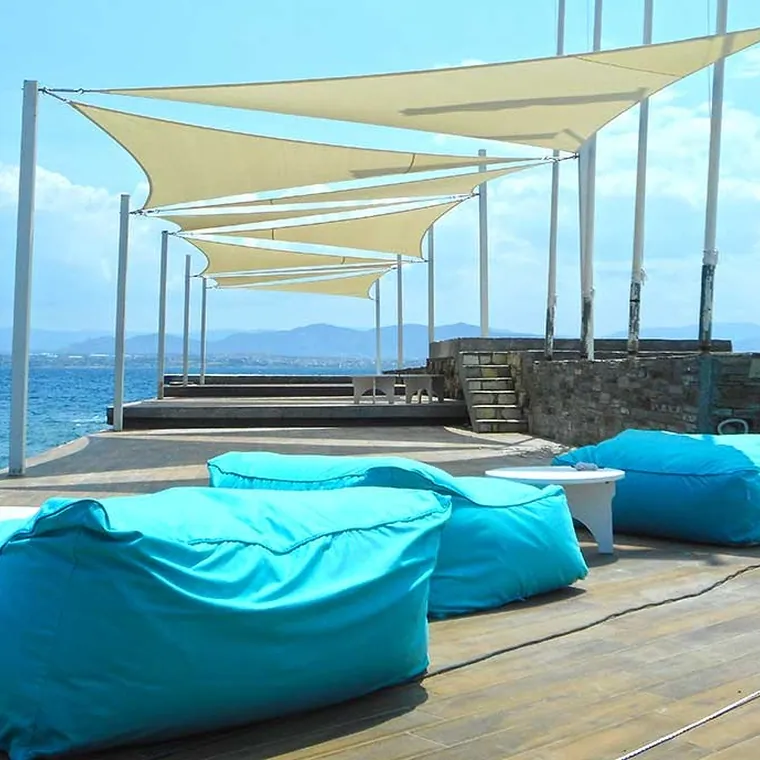 Cream shade sails over a sun deck with beanbags by the water