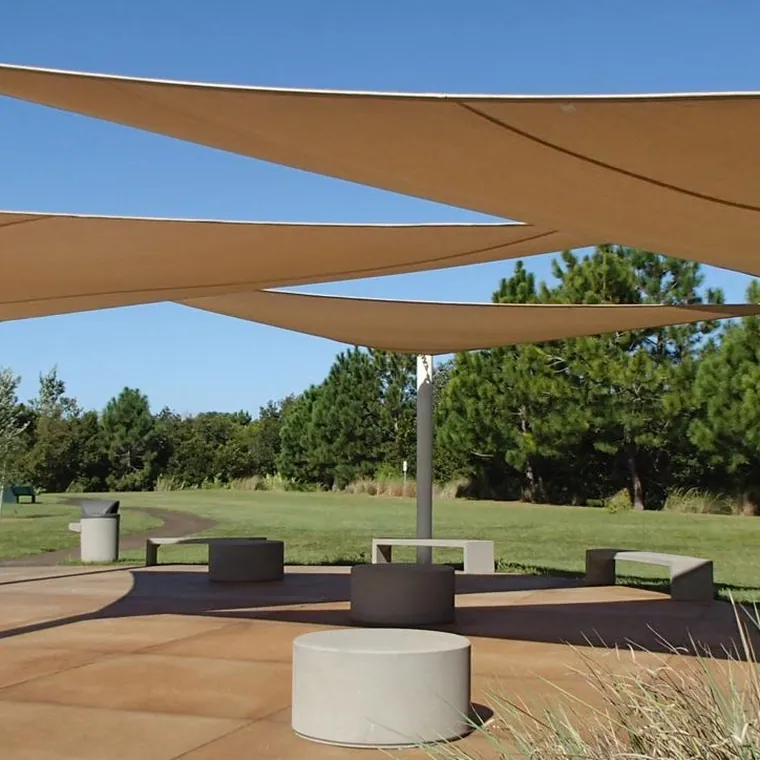 Tan shade sails on tall masts over an open lawn