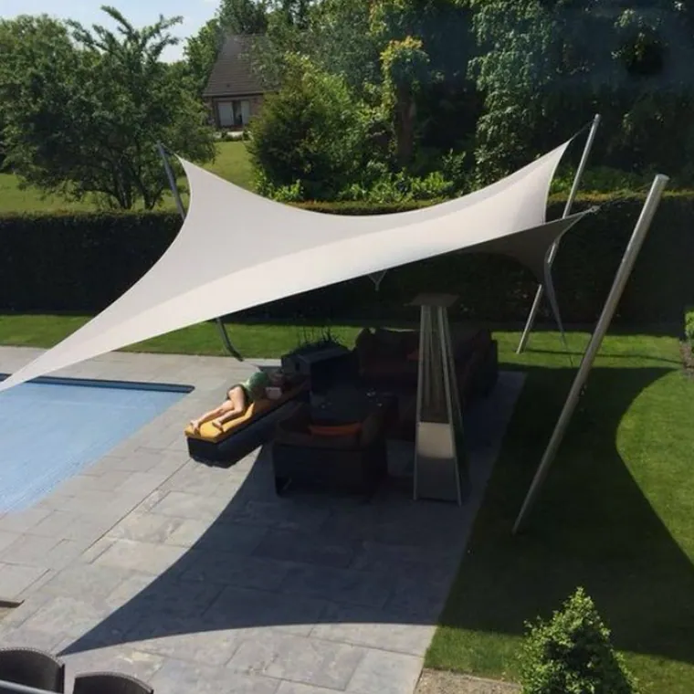 White shade sail over a poolside seating area at dusk