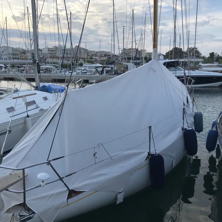 Sailing yacht in a marina under a full pale grey winter cover