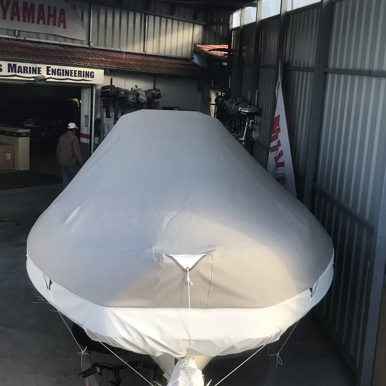 RIB under a fitted white cover, stored inside the workshop