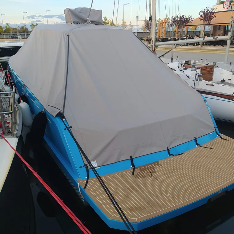 Grey cover tented over the teak deck of a yacht, cabin windows left clear
