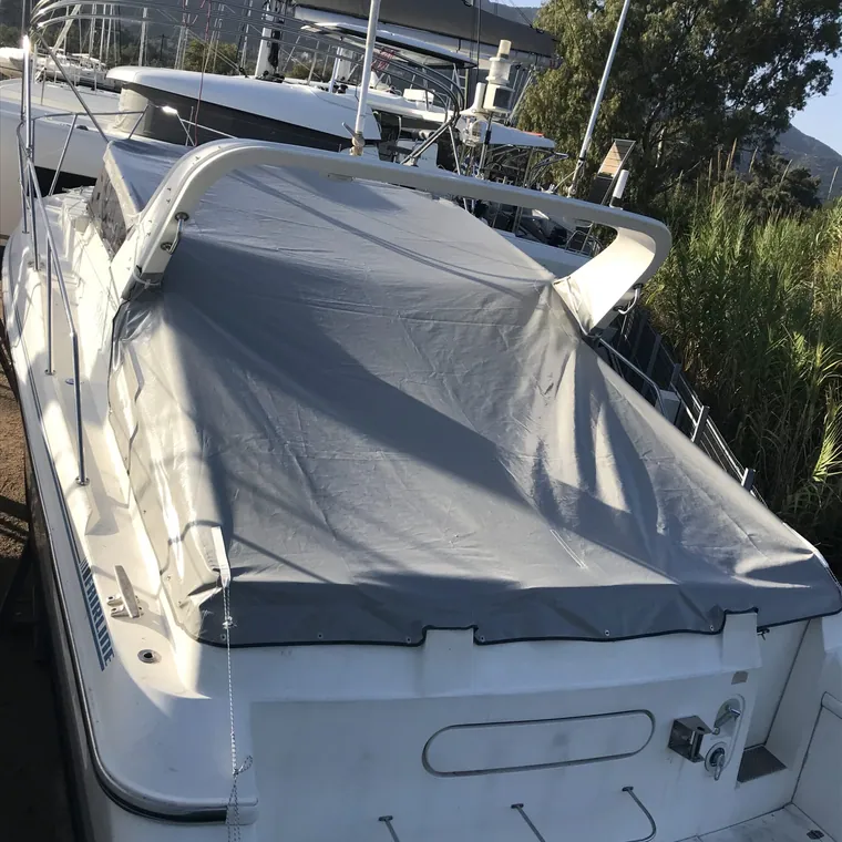 Motor yacht in a marina with cockpit and flybridge under a grey cover