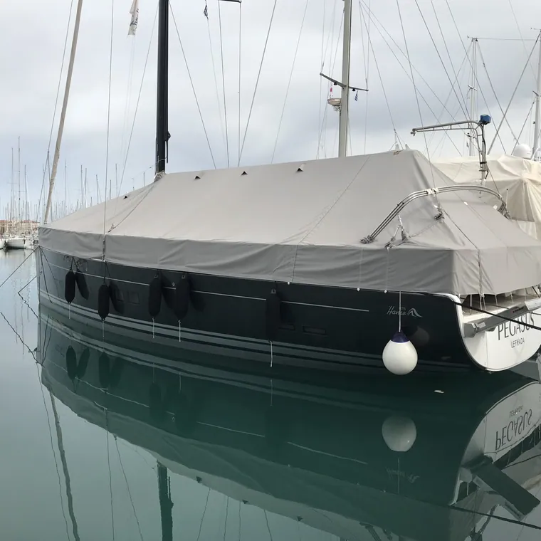 Covered yacht mirrored in still harbour water