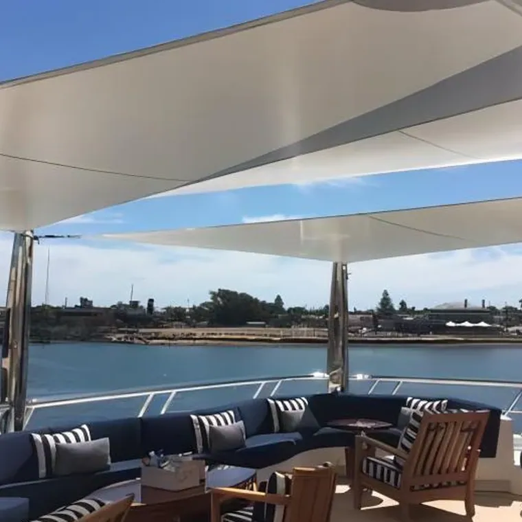 Deck seating and low tables shaded by tensioned white sails