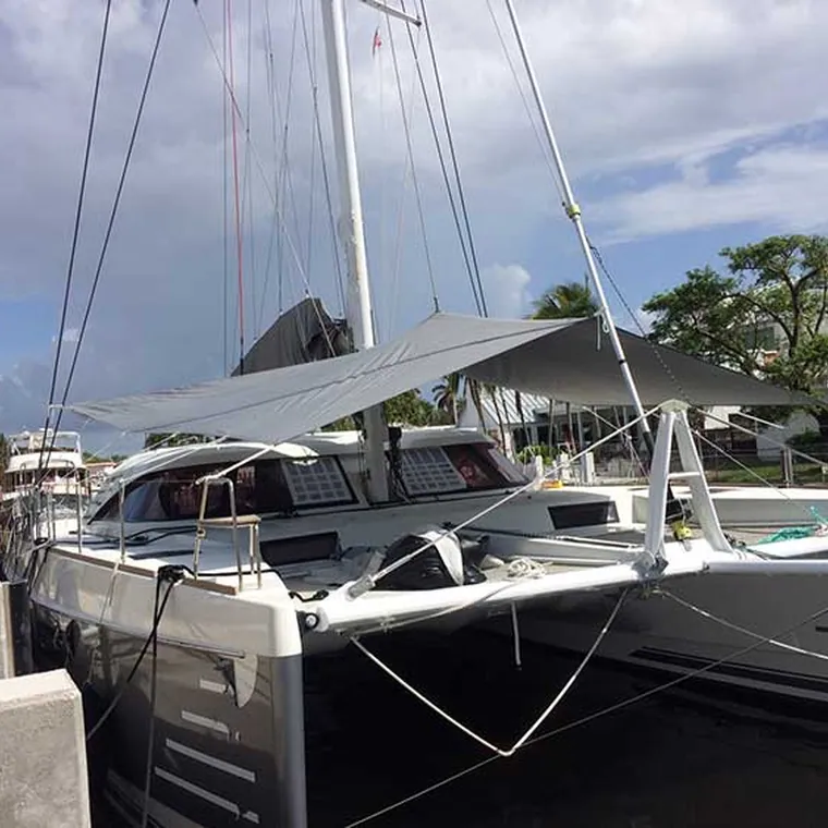Catamaran in a marina with a shade sail rigged over the trampoline