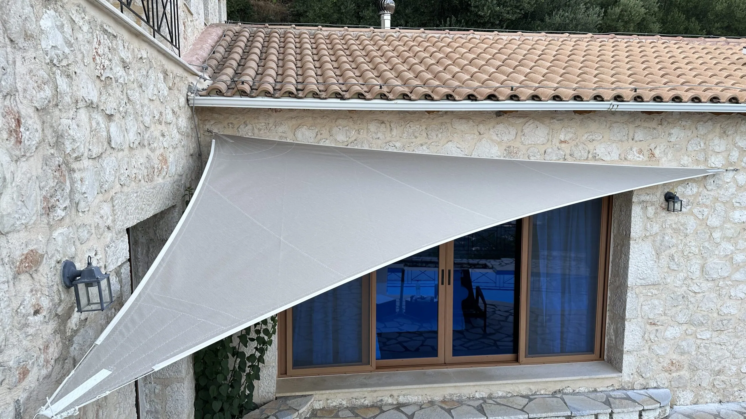A shade sail tensioned over a terrace ashore